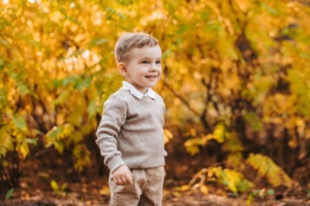 Cheerful boy in casual outfit having fun at the Park in autumn.