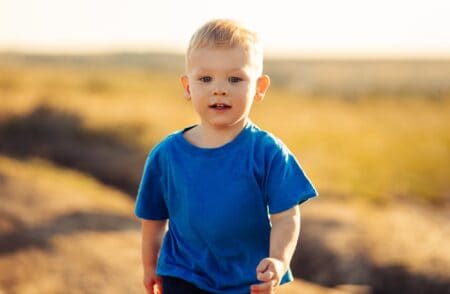 Happy little boy walking in the field