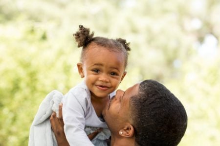 A father lifting up his African baby girl