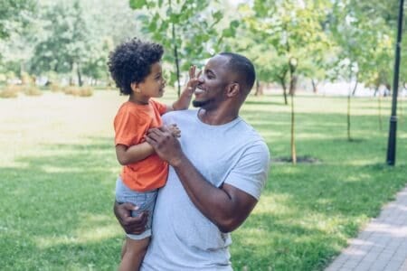 African dad carrying his son at the park