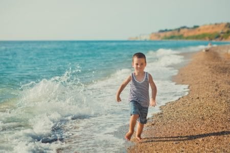 Cheerful boy running on beautiful beach