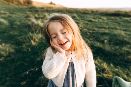 Cheerful pretty young girl posing for the camera in the field on sunny day