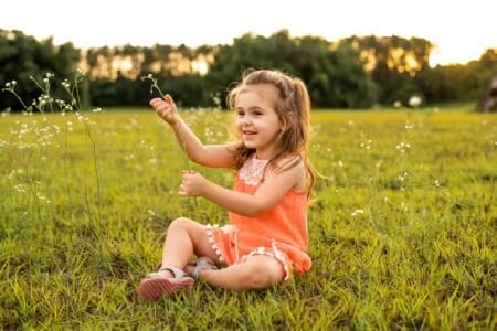 Adorable little girl sitting on the grass at the park