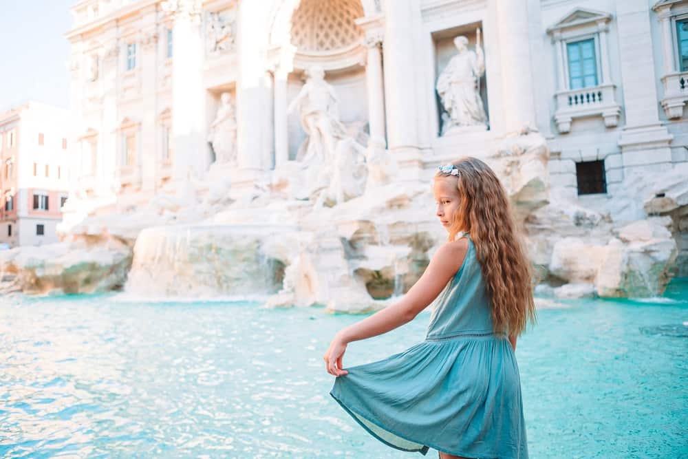 Little girl holding her dress near fountain