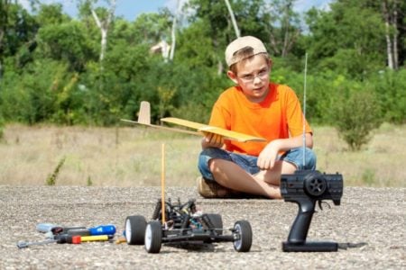 Young boy sitting on the ground playing with remote controlled car