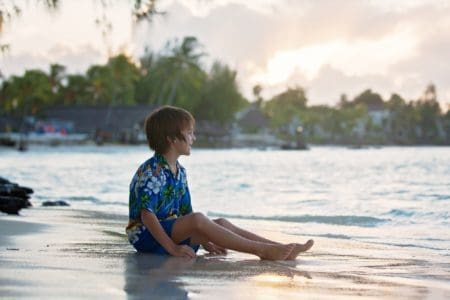 A happy Hawaiian boy on the beach looking at the ocean