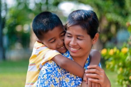 Native American boy hugs his mother in the park