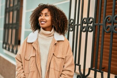 Happy black african american woman standing against window grills