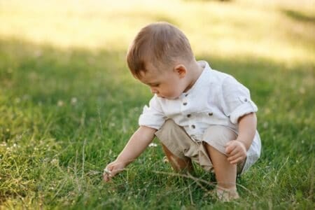 Baby boy sitting on the grass in the park on summer day