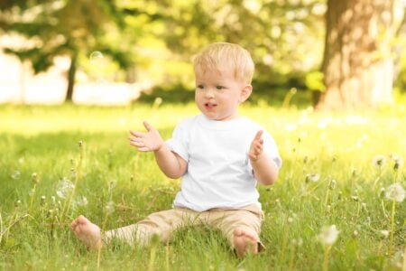 Little boy sitting on the grass in the park.