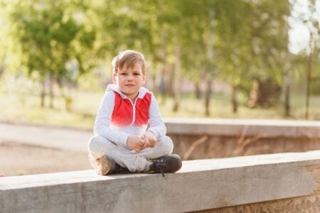 Handsome boy sitting on the bench in the summer outdoors