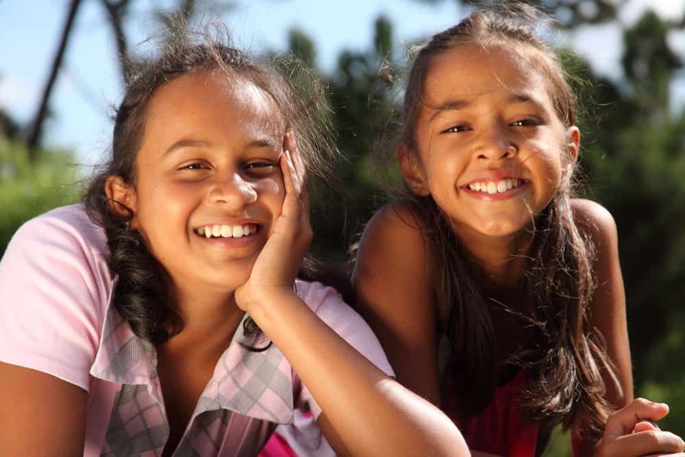 Two smiling Brazilian girls are playing in the park