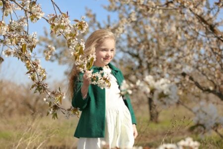 Cute little girl standing near the tree in the park