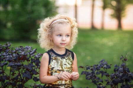 Young pretty girl with curly hair plays in a summer park