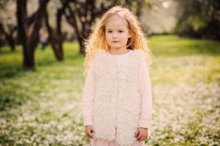 Adorable little girl walking in blooming spring garden