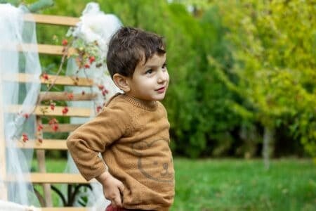 Cute little boy in sweater standing at the park