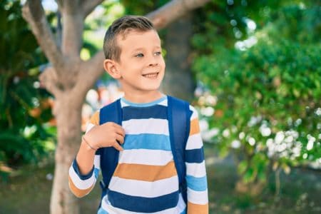 Smiling young student boy standing at the park