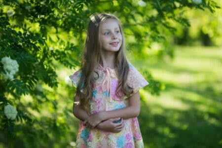 Beautiful girl standing near a blossoming tree in the park