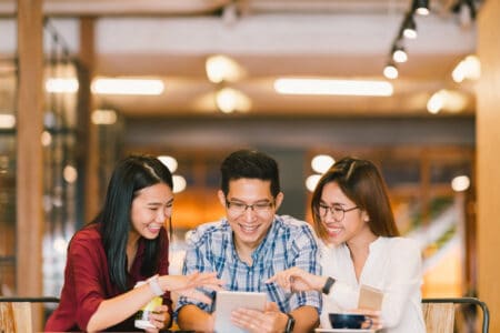 Group of happy adults using digital tablet at coffee shop