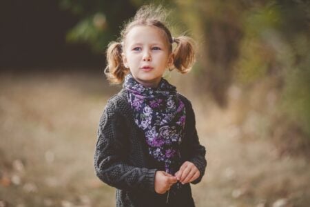 Little girl in black cardigan walking in the park.