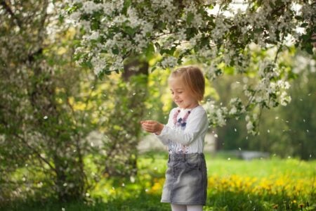 Lovely girl in blooming apple orchard in sunny spring day