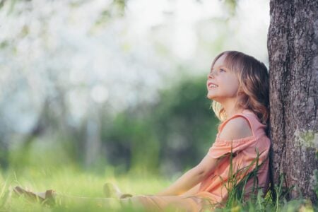 Happy girl sitting under a tree.