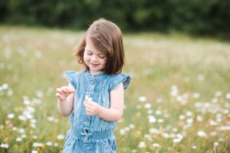 Happy little girl looking at the flower in her hand