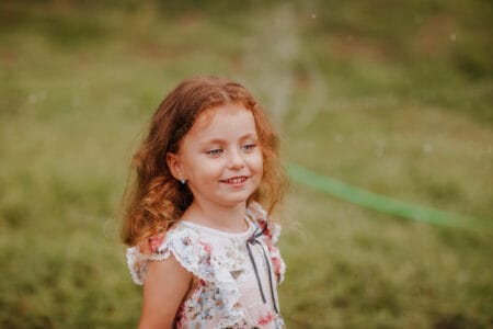 Young pretty curly girl in summer dress on green glade