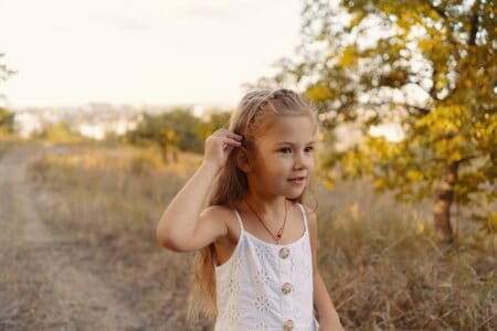 Lovely little girl wearing white clothes playing in the nature