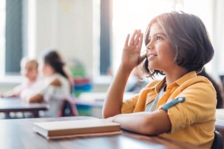 Italian girl raising her hand to answer the teacher's question