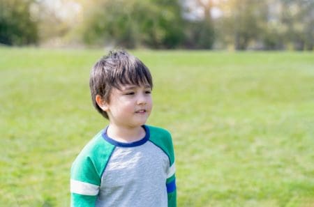 Happy young boy standing in grassy field