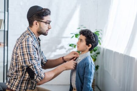 Jewish dad fixing his son's clothes