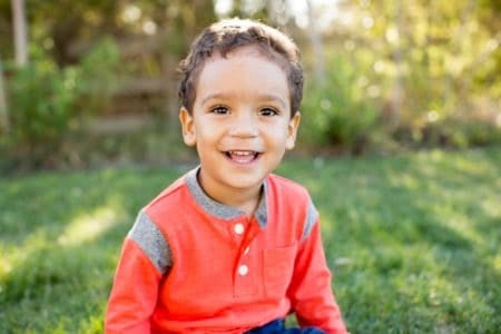 Happy little boy sitting in the grass outdoor