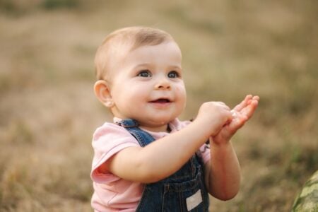 Cute baby in denim overalls eating a watermelon