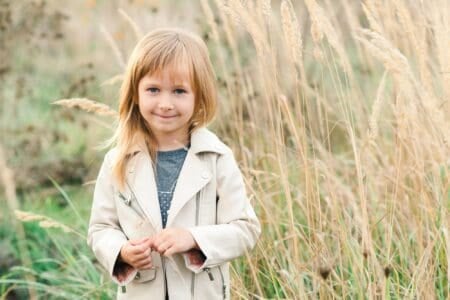 Adorable blonde little girl smiling in the meadow