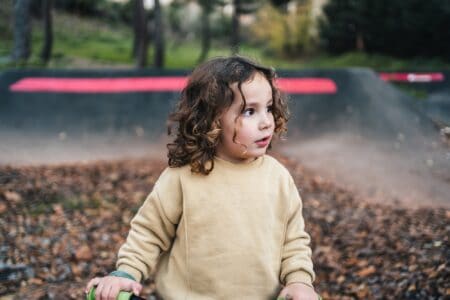 Handsome little boy with curly brown hair standing outdoor