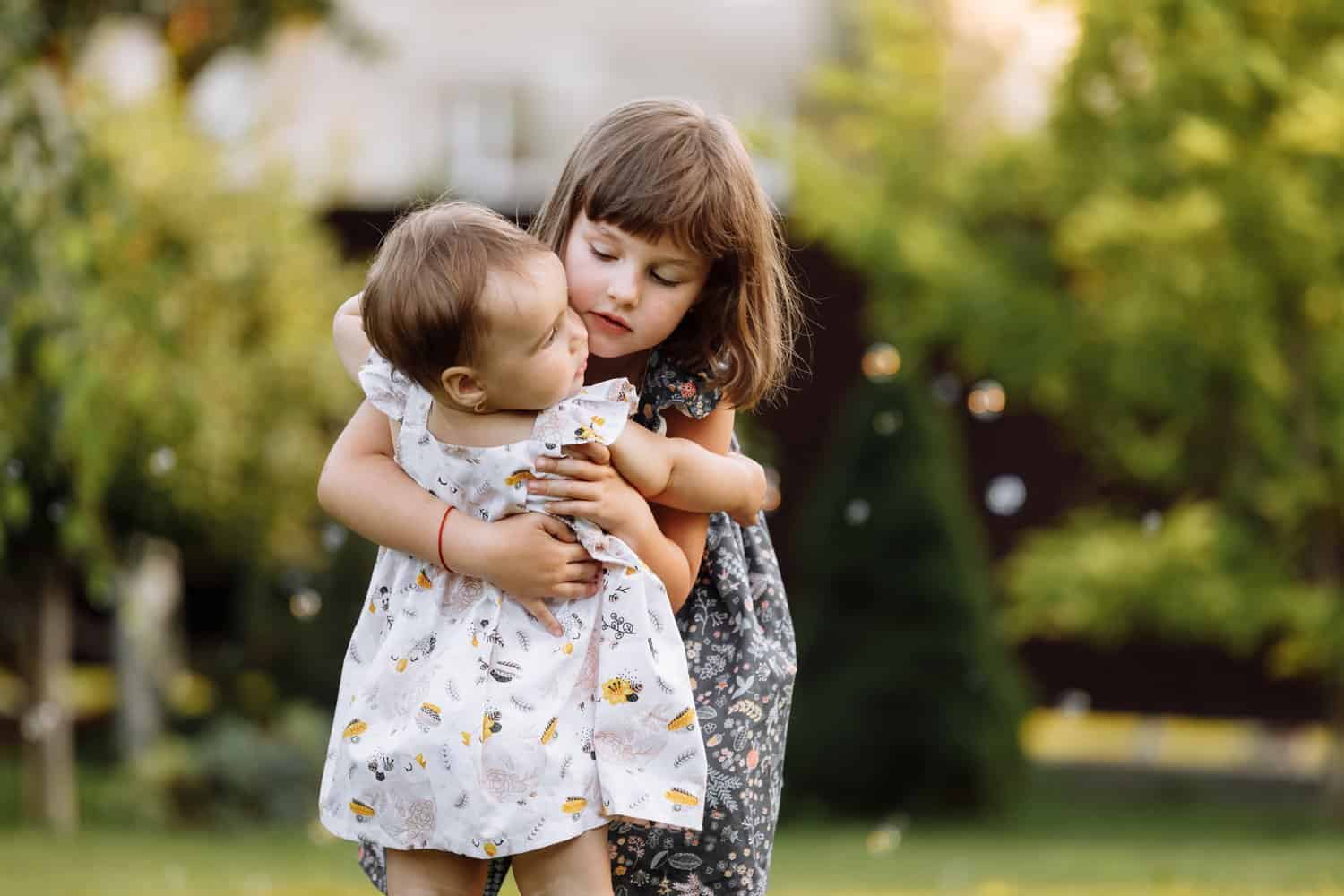 Two girls hugging outdoors in nature on summer day