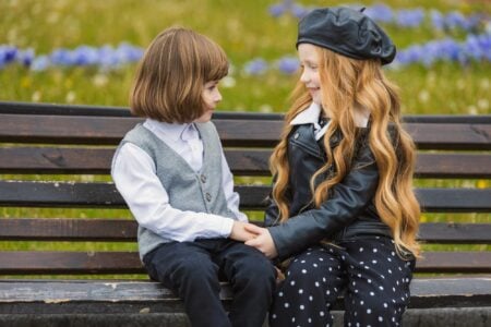 Stylish kids sitting on a bench and looking at each other