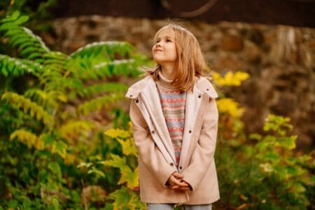 Adorable young blonde girl wearing jacket having fun at the park