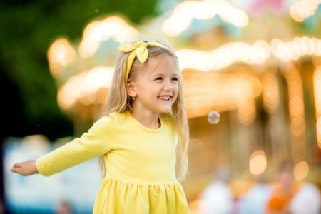 Happy little girl spending time in the amusement park