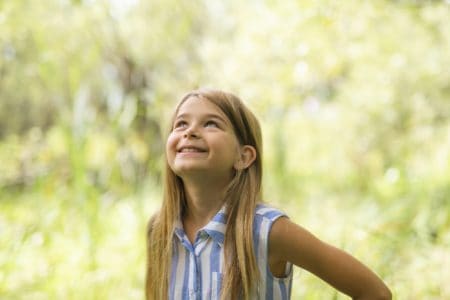 Happy young girl looking up in the park