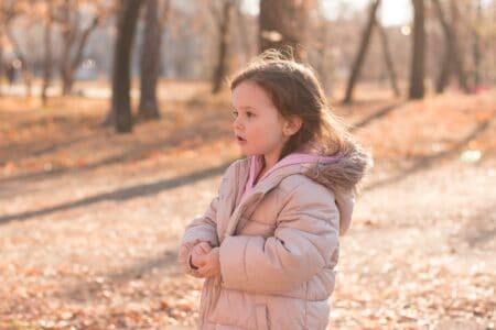 Young girl in warm coat standing in a cold autumn street