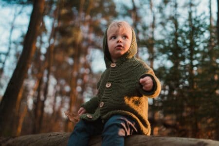 Low angle view of little curious boy sitting on a log