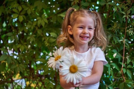 Happy little girl holding a camomile