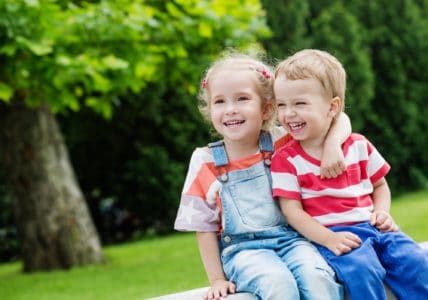 Little boy and girl sitting on the bench in the park