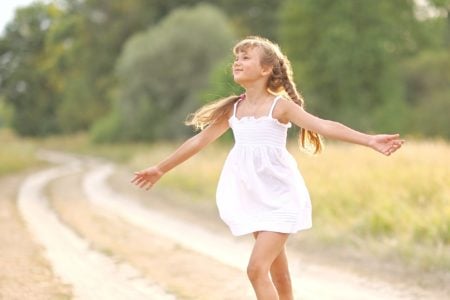 Beautiful young girl in white dress enjoying the summer sun