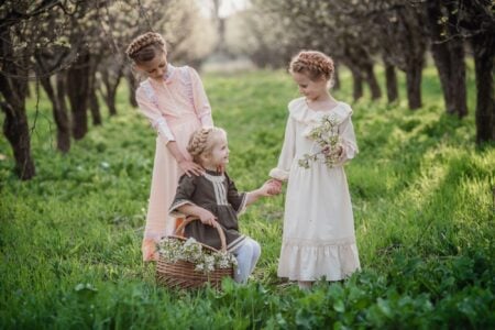 Three girls in medieval dresses playing in the garden.