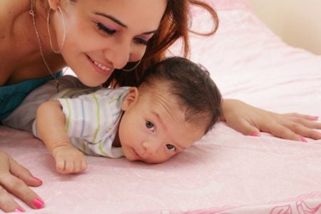 A hispanic mother leaning over her baby