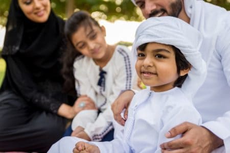 Happy Middle Eastern boy and girl spending time with their parents in the park