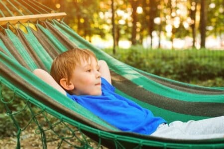 Cute boy relaxing in hammock in the garden